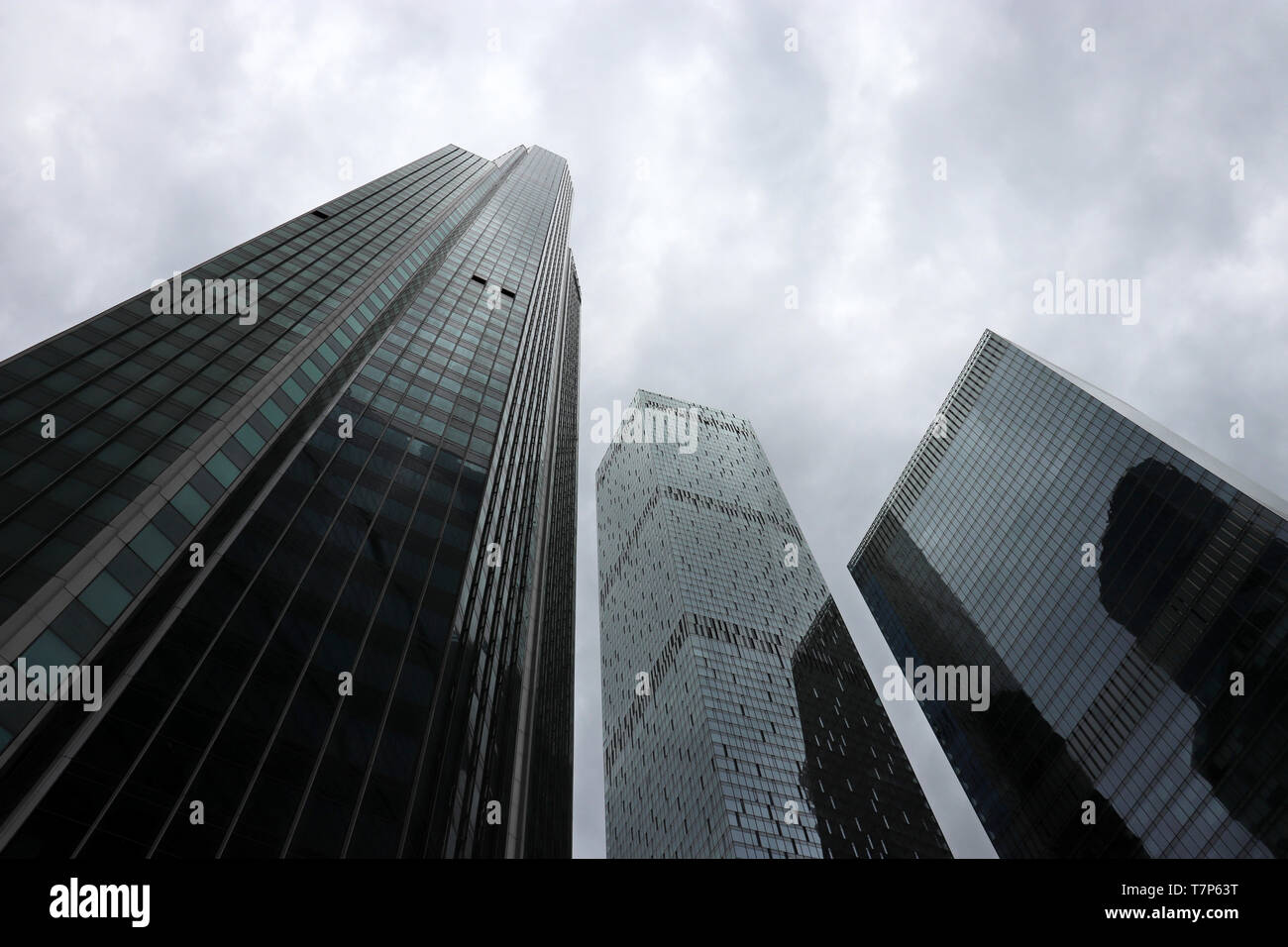 Grattacieli in stormy sfondo con cielo nuvoloso, vista dal basso. Città futuristica con drammatica sky, architettura moderna, concetto di urbanizzazione Foto Stock