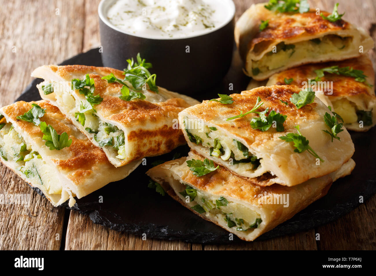 Bolani afghano con purea di patate e cipolle verdi servita con yogurt bianco closeup sul tavolo orizzontale. Foto Stock