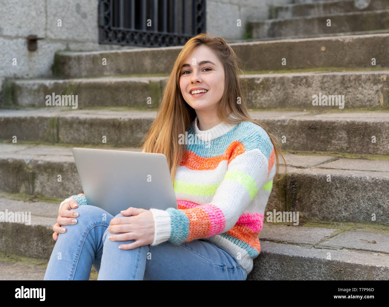 Attraente trendy teen studente o una giovane studentessa lavorando sul portatile su internet, blog, chat e posta elettronica di controllo sulle operazioni in una comunità c Foto Stock