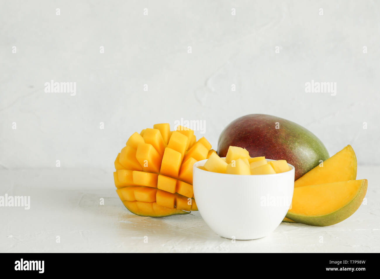 Una piccola ciotola con pezzi di mango e tagliare i manghi su sfondo bianco, spazio per il testo Foto Stock