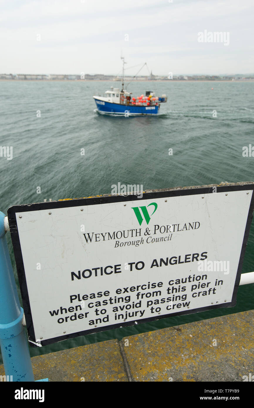 Una barca da pesca passando un segno sul Weymouth della pietra Pier consigliare i pescatori a diffidare di compromettere il passaggio di navi ed equipaggi durante la colata. Weymouth Dorset en Foto Stock