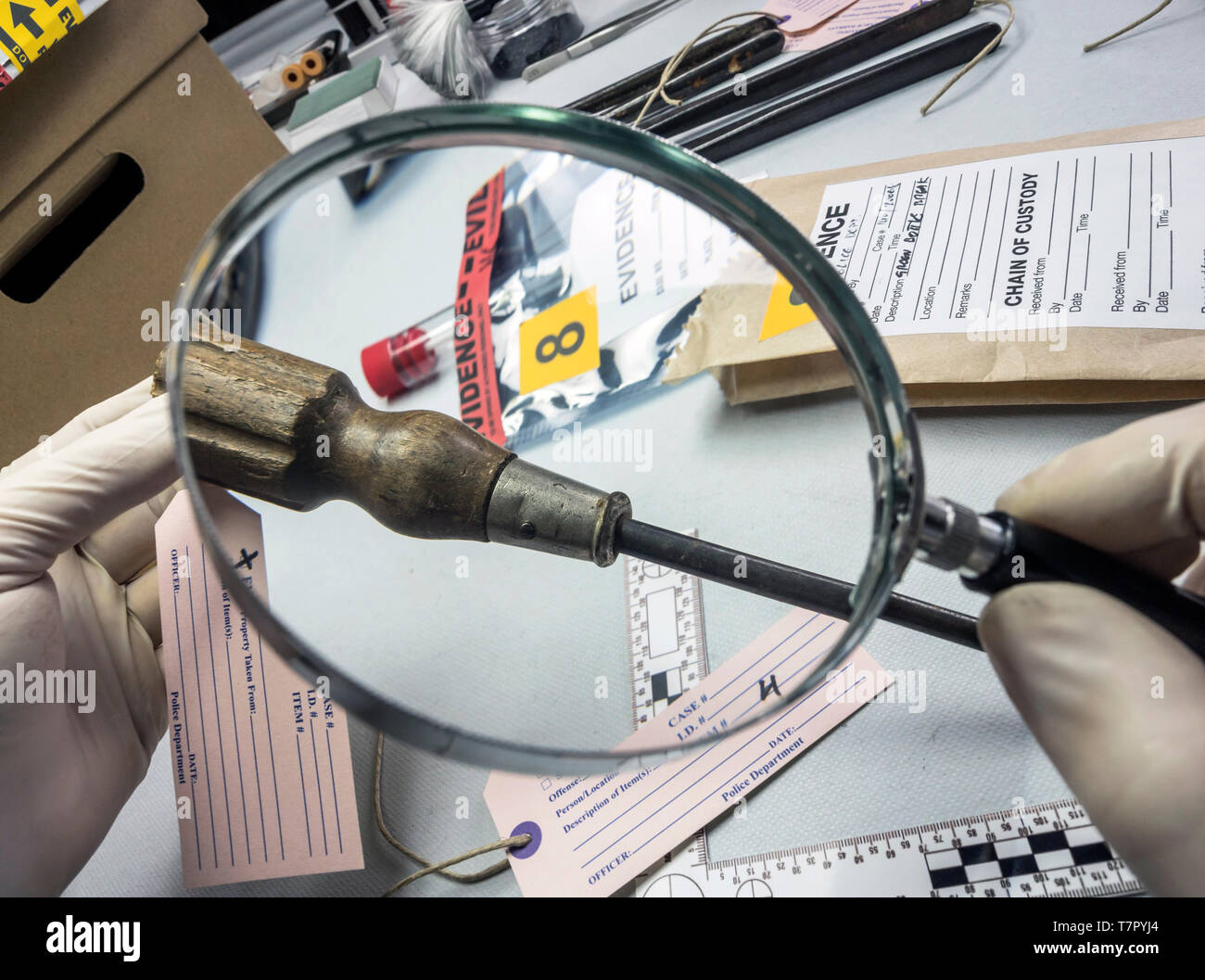 La polizia di esperti esamina con la lente di ingrandimento di un cacciavite nel laboratorio di medicina legale attrezzature, immagine concettuale Foto Stock