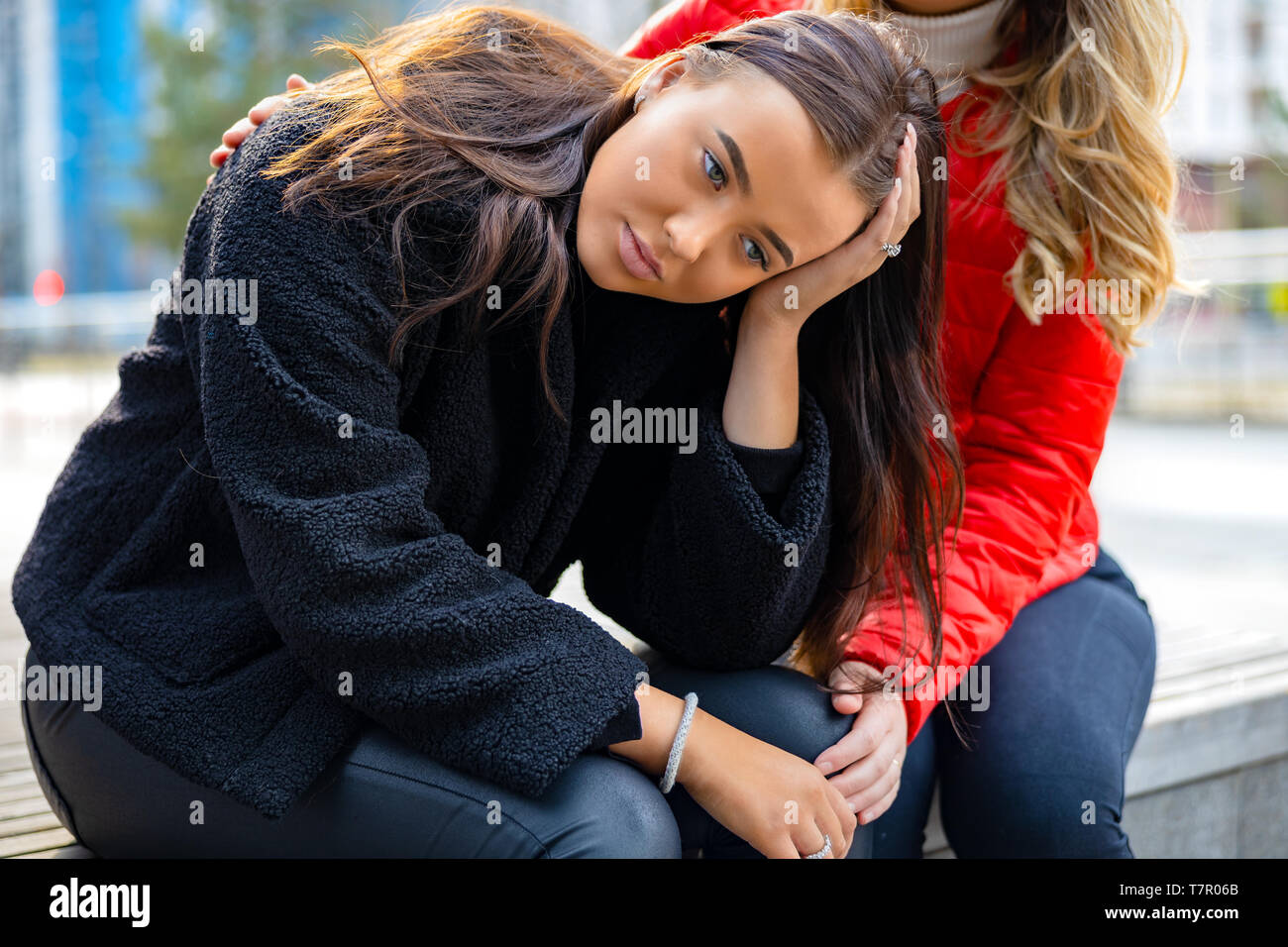 Amico consolante infelice giovane donna in città Foto Stock