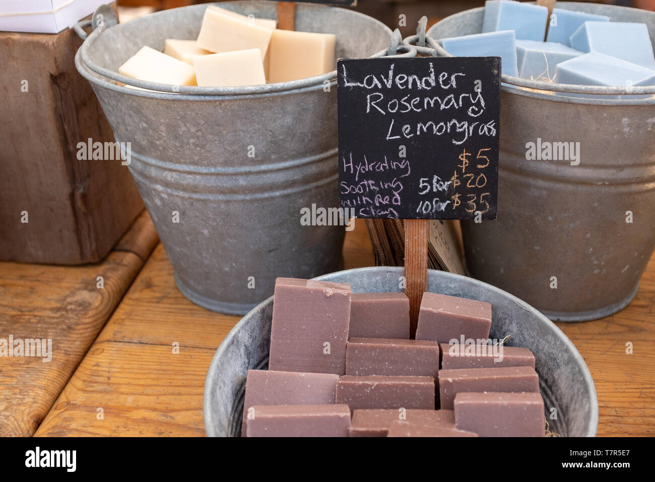 Un close up foto di barre di colorati fatti in casa sapone in grandi bidoni in metallo per la vendita in un mercato degli agricoltori Foto Stock