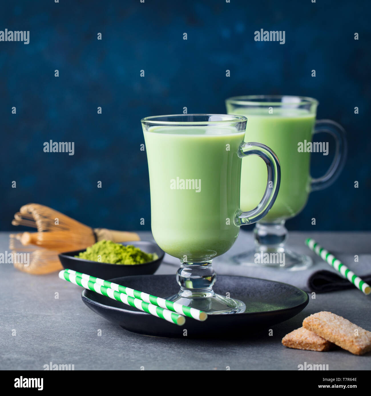 Tè verde Matcha latte e mescolare con una frusta di bambù. Grigio e blu sullo sfondo. Copia dello spazio. Foto Stock