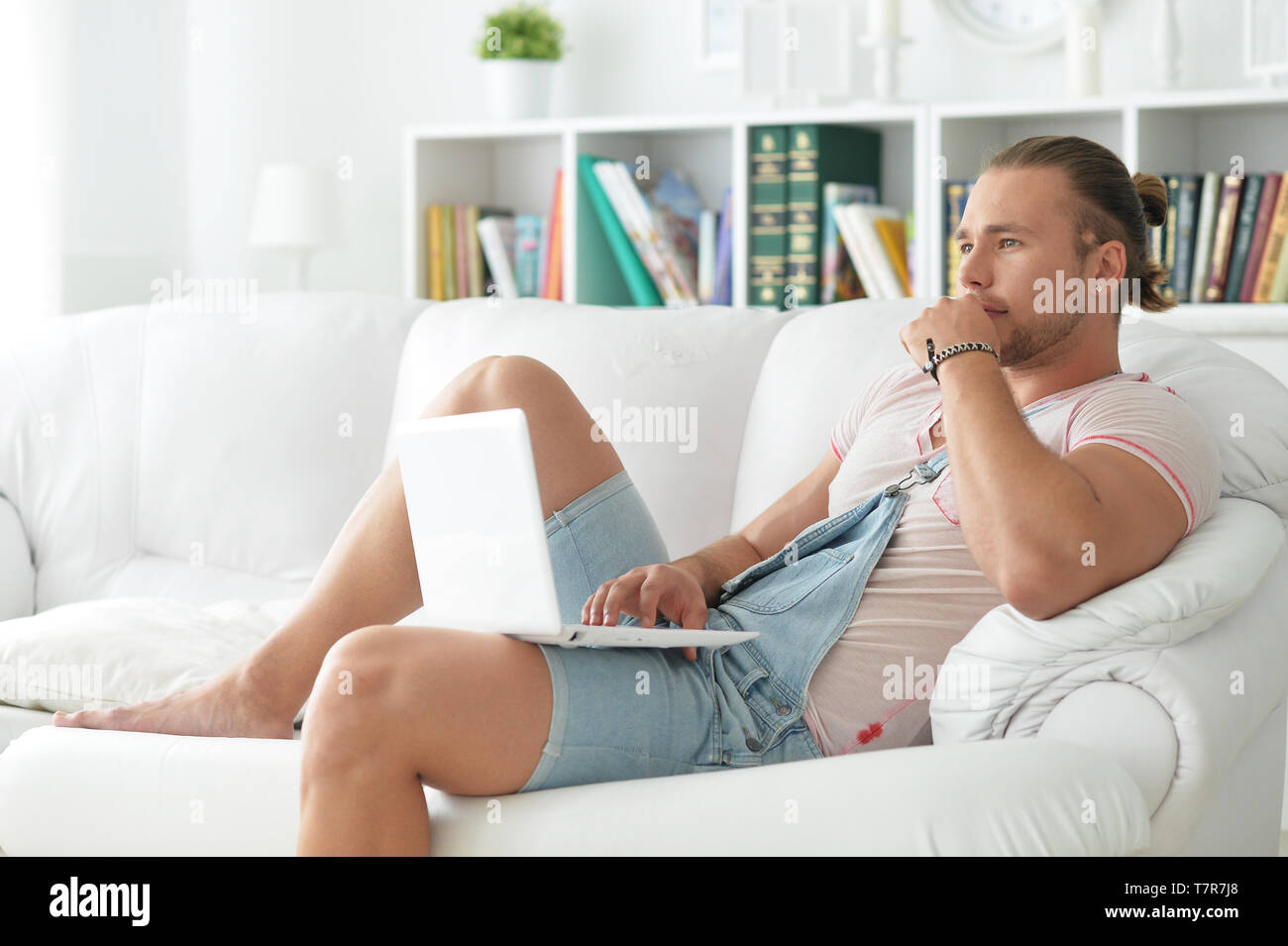 Ritratto di giovane uomo parigamba trascorrendo del tempo con il portatile a casa Foto Stock