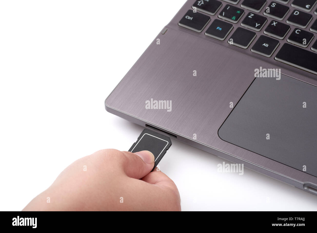 Vista ravvicinata di donna con la mano nera della scheda SD. Si collega a un lettore in argento di un portatile con una tastiera. Isolato su sfondo bianco. Foto Stock