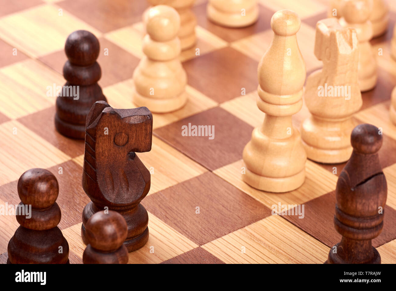 Vista ravvicinata della partita a scacchi con il bianco e nero di pezzi di registro sulla scacchiera marrone. Lotta o rivale con cavallo e pegni. Foto Stock