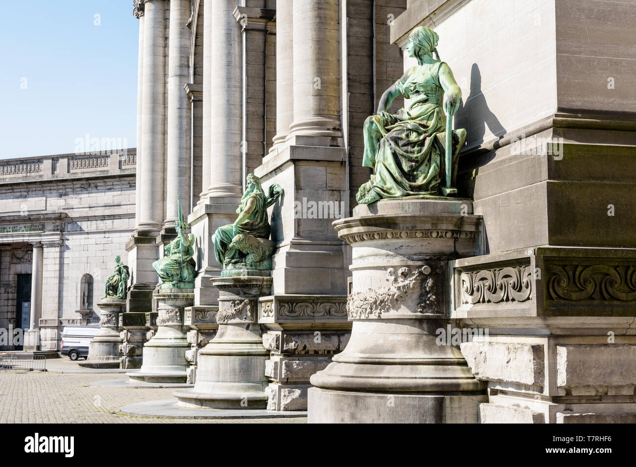 Vista ravvicinata delle statue alla base delle colonne sul lato orientale del porticato du Cinquantenaire, l'arco trionfale a Bruxelles, in Belgio. Foto Stock