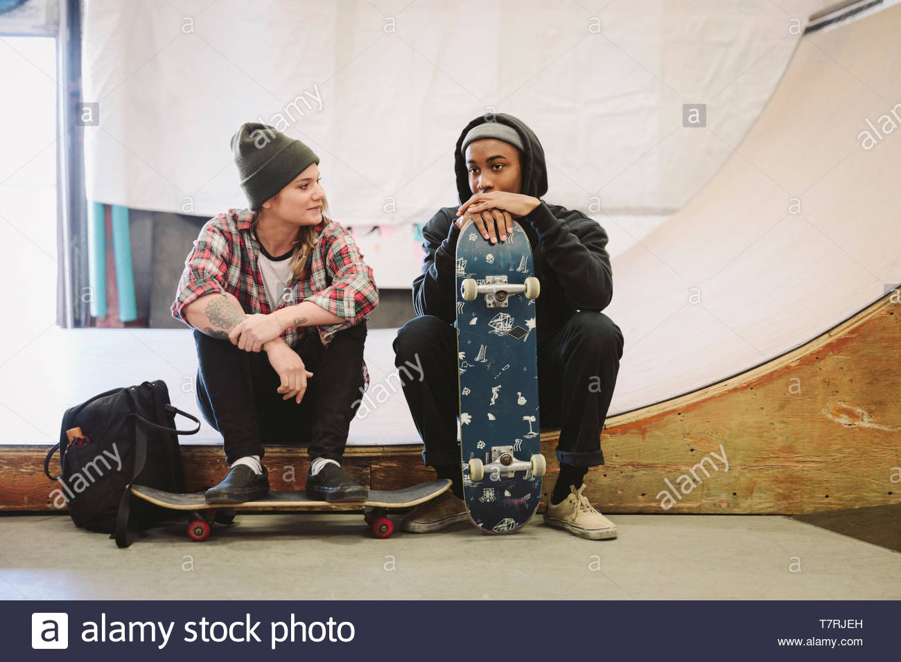 Giovani skateboarders parlando a indoor skate park Foto Stock