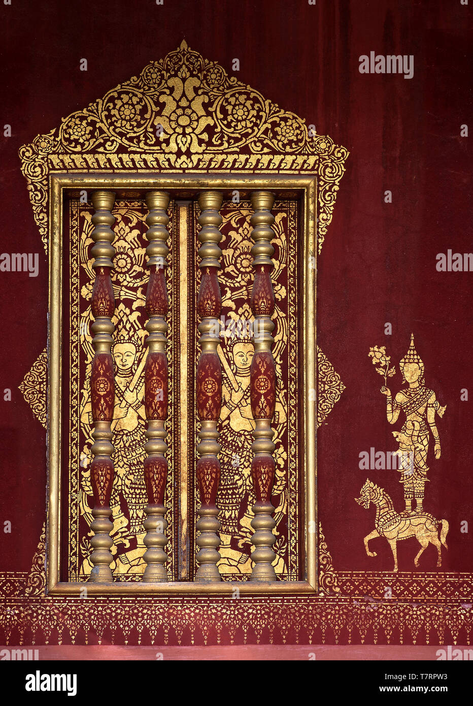 Windows con accenti di Khmer-stile balaustre in legno dorato e murales stencil di una divinità, tempio Wat Sensoukharam, Luang Prabang, Laos Foto Stock