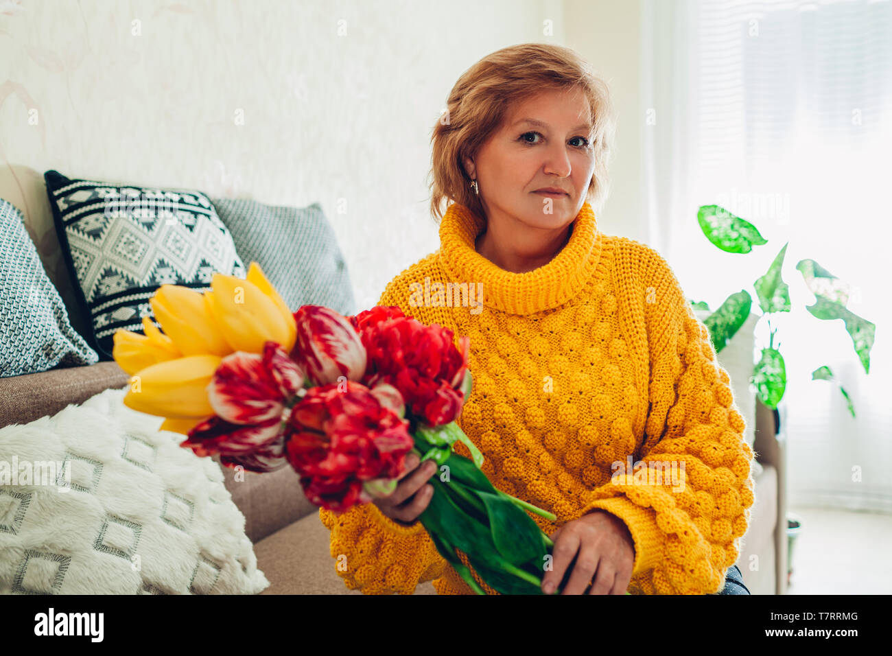 Senior donna holding bouquet di tulipani da i suoi bambini a casa. Giornata della madre presente Foto Stock