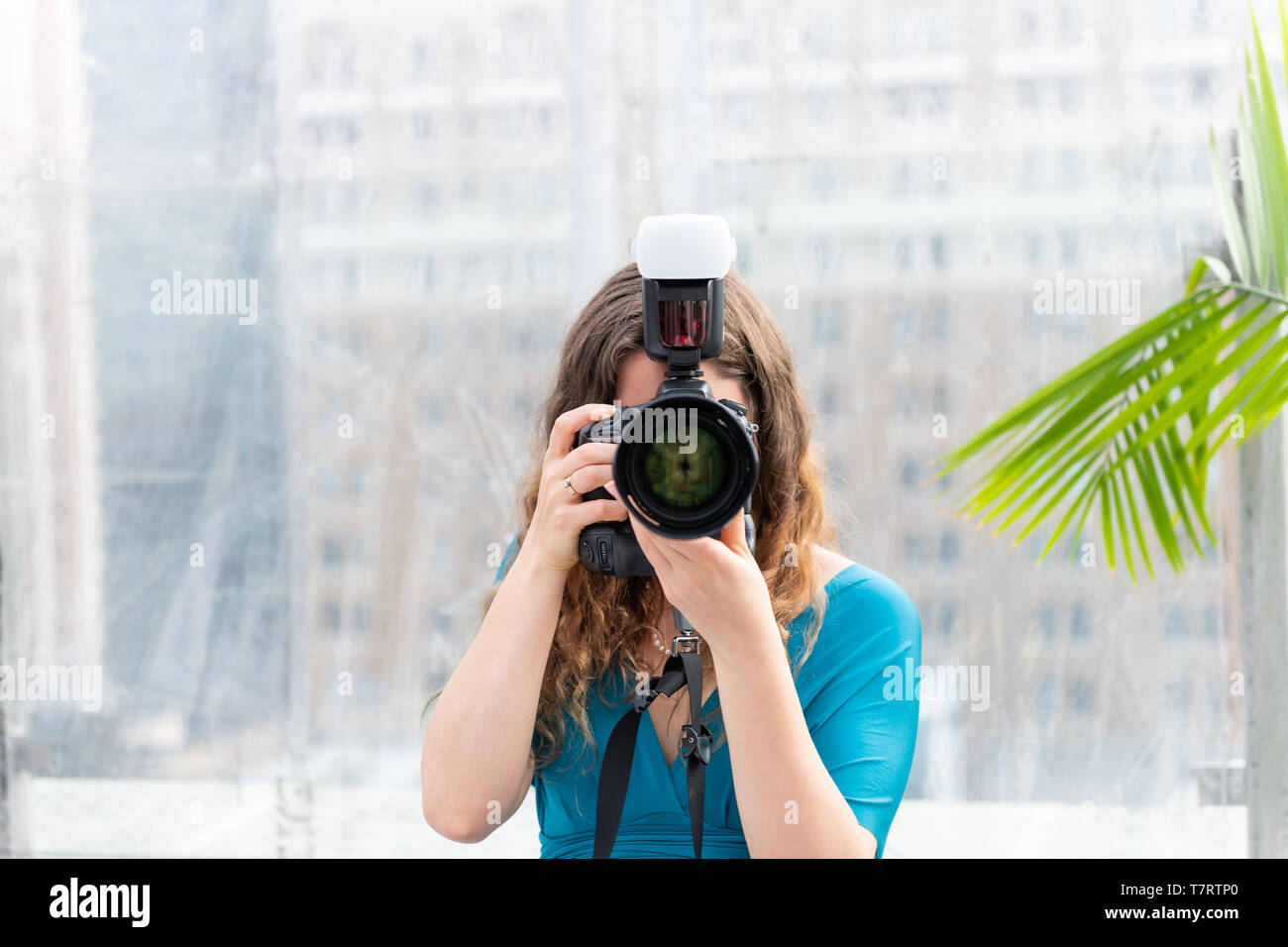 Un giovane fotografo per matrimoni donna abito in piedi con la fotocamera flash esterni tenendo immagine fotografia e la lente che ricopre la faccia Foto Stock