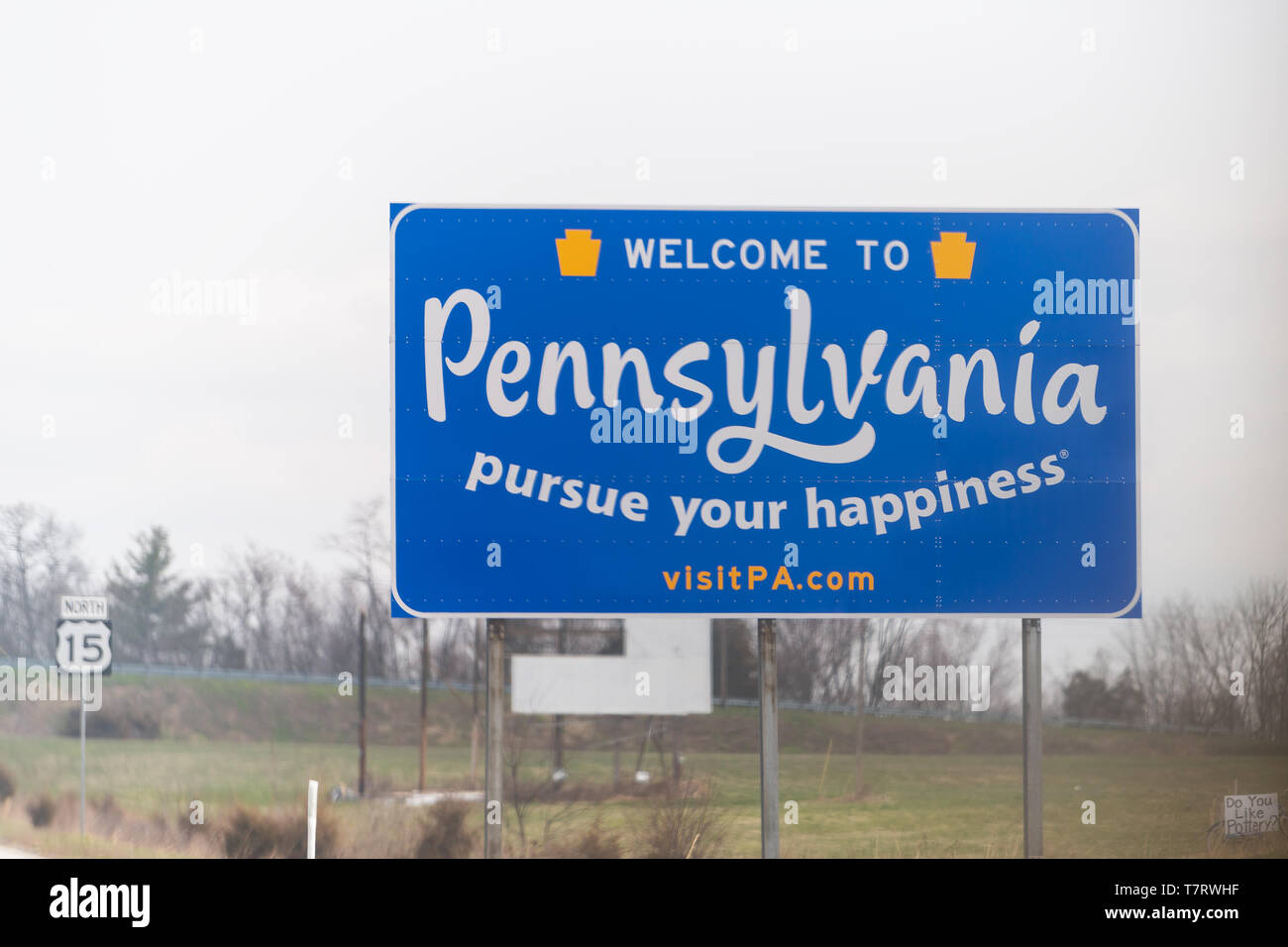 Emmitsburg, STATI UNITI D'AMERICA - Aprile 6, 2018: segno blu sull'autostrada 15 in Pennsylvania o Maryland con benvenuti al segno di stato e perseguire la felicità con sito web Foto Stock