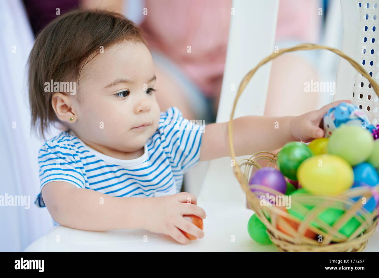 Baby girl mettere le uova di pasqua a busket sul ricongiungimento familiare Foto Stock