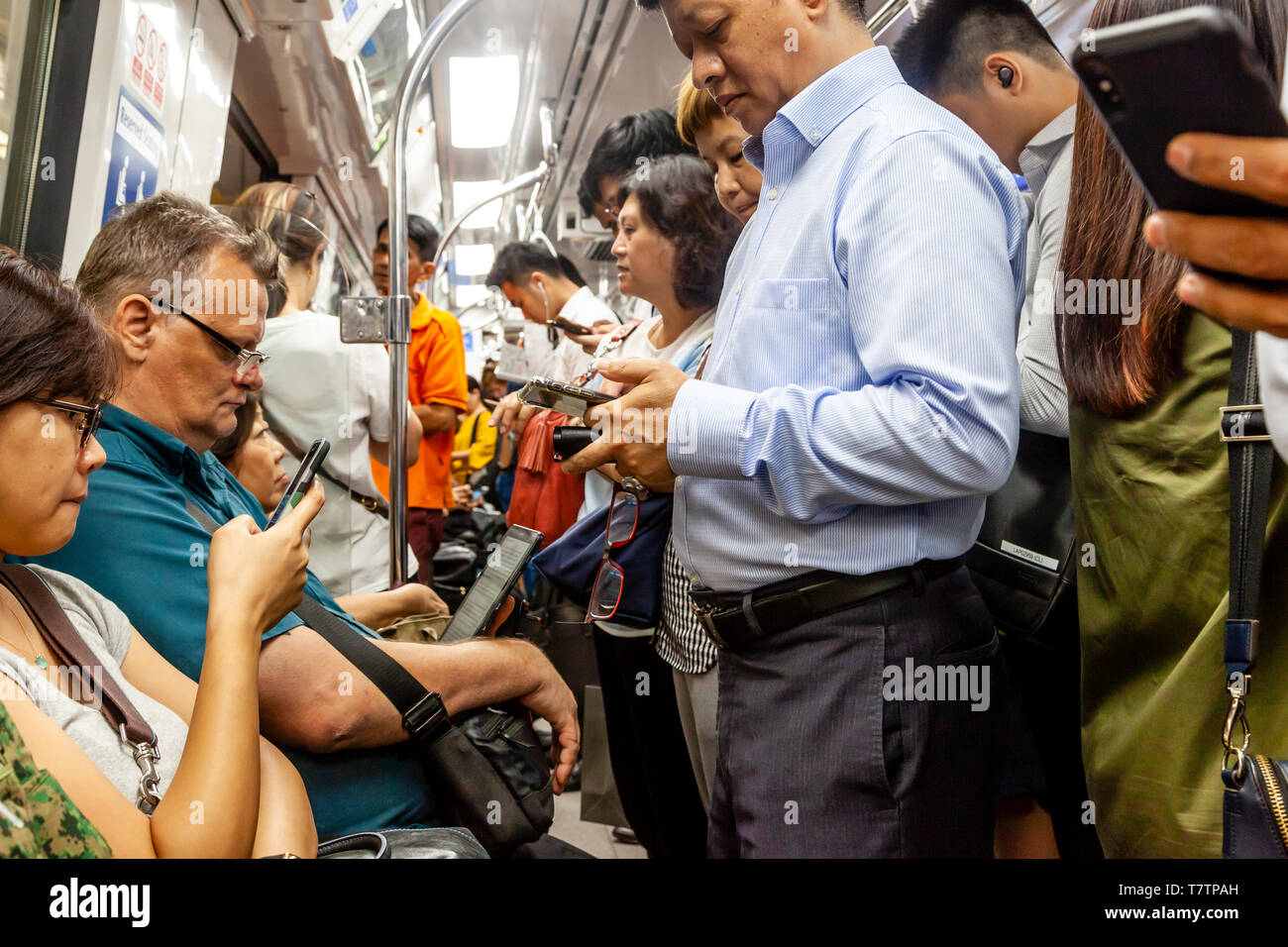 Persone che guardano il loro smartphone su MRT, Singapore, Sud-est asiatico Foto Stock