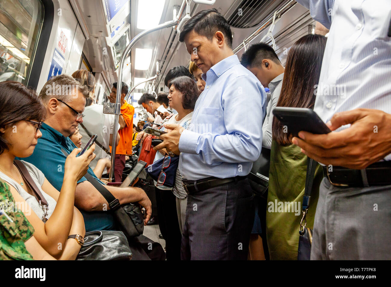 Persone che guardano il loro smartphone su MRT, Singapore, Sud-est asiatico Foto Stock
