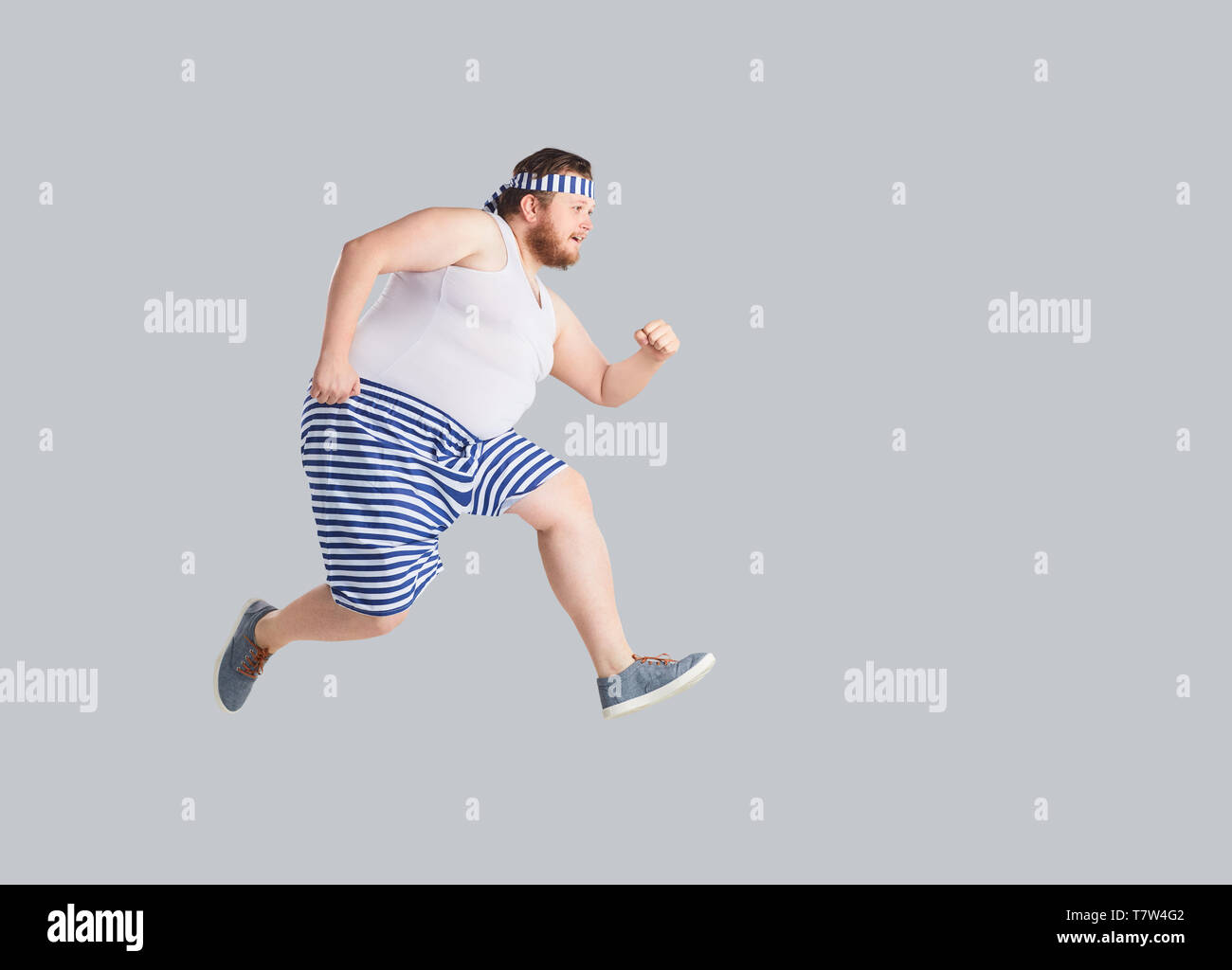 Funny Man in pantaloncini a strisce viene eseguito su uno sfondo grigio. Foto Stock