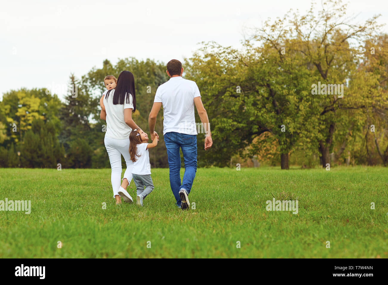 Vista posteriore. Famiglia con bambini passeggiate nel parco. Foto Stock