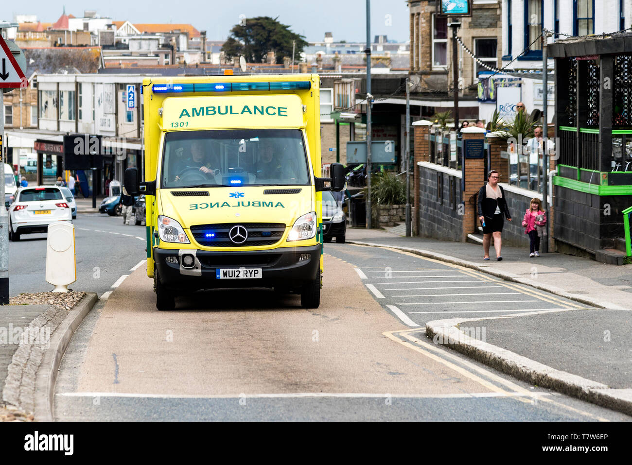 Un'ambulanza NHS con luci blu in risposta a una chiamata d'emergenza a Newquay, in Cornovaglia. Foto Stock