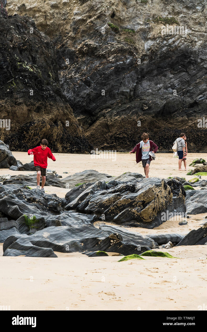 Giovani vacanzieri ad esplorare le rocce a bassa marea su Towan Beach in Newquay in Cornovaglia. Foto Stock