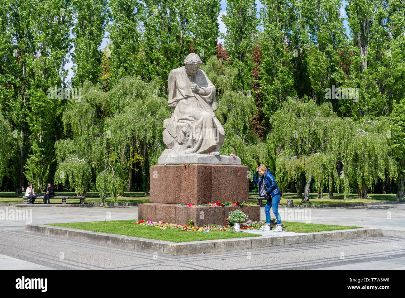 Una donna getta fiori in pianto patria statua alla guerra sovietica Memorial (Sowjetisches Ehrenmal) a Berlino Treptow, Germania Foto Stock