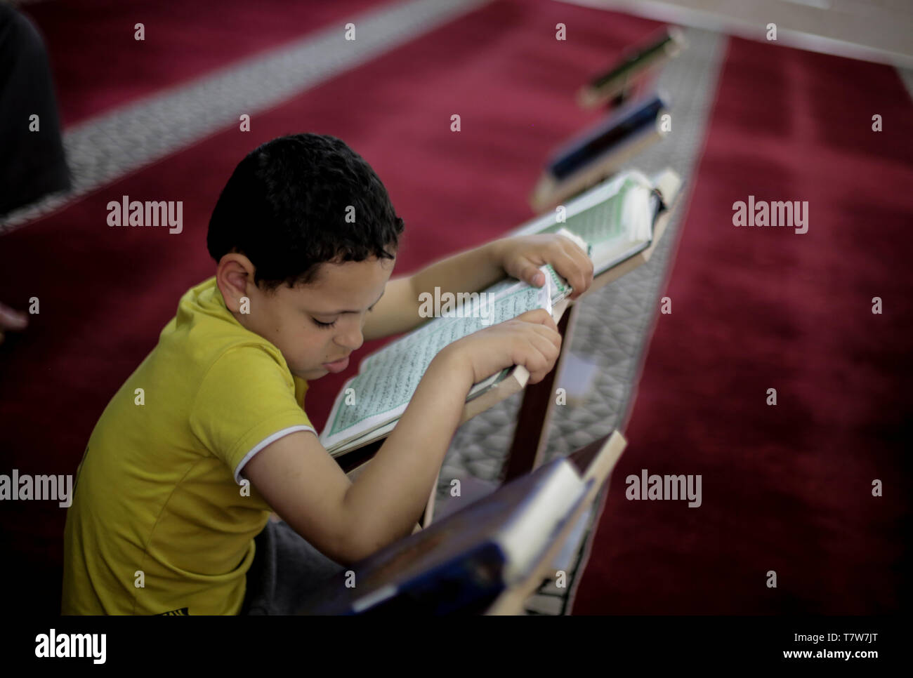 Ragazzino palestinese visto la lettura del Corano alla moschea di luce durante il Ramadan. Con il sostegno della Jihad islamica, circa 10.000 bambini e ragazzi consente di memorizzare il Corano per 60 giorni. Terzo giorno del Ramadan. I musulmani di tutto il mondo partecipano al santo il mese di digiuno del Ramadan, il più sacro mese del calendario islamico, astenendosi dal mangiare, bere e fumare dall alba al tramonto. Foto Stock