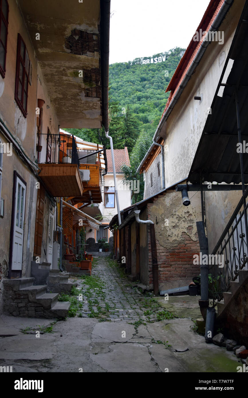 Cortile stretto in Brasov con 'Brasov' firmare a Tampa mountain. Foto Stock