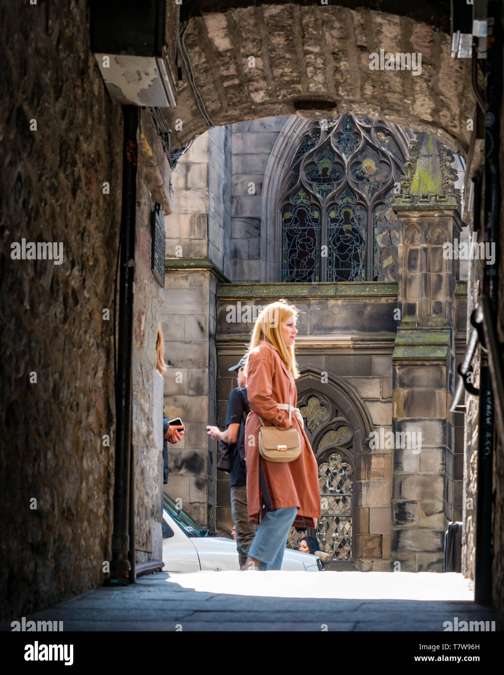 Vicolo di ingresso si pronuncia a favore di una stretta con vista della Cattedrale di St Giles vetrata. Pretty Woman walking passato, Royal Mile di Edimburgo, Scozia, Regno Unito Foto Stock