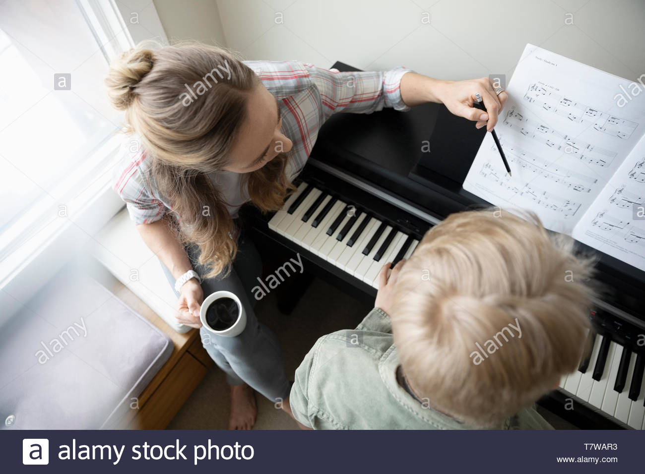 Madre figlio aiuta a fare pratica al pianoforte Foto Stock