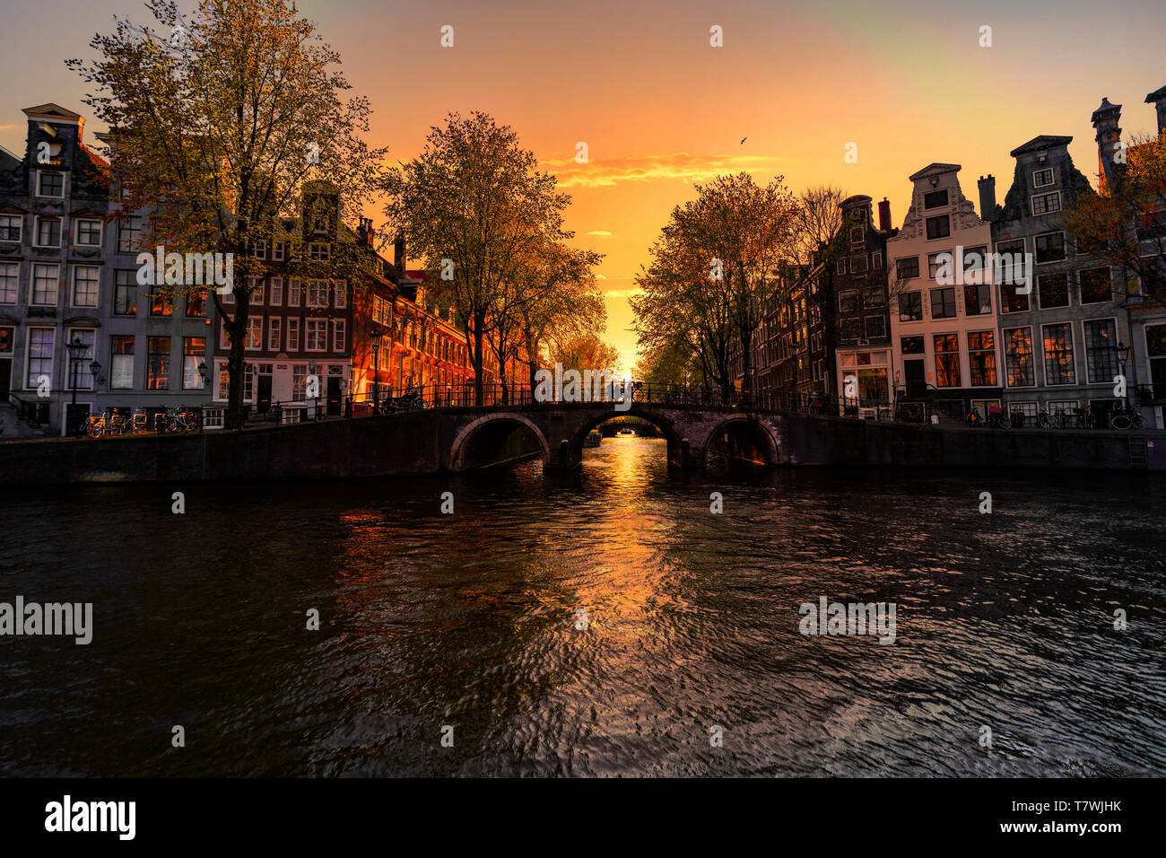 Tramonto sul case di Amsterdam e canal riflessa sulle acque del canal, Amsterdam, Paesi Bassi Foto Stock