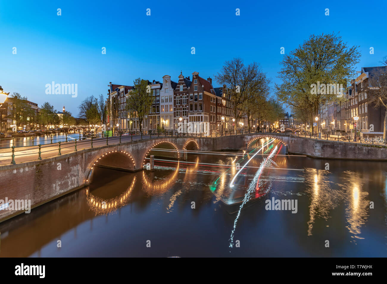 Esposizione lunga crociera in barca lungo la calma di Amsterdam canal al tramonto blu ora, Paesi Bassi Foto Stock