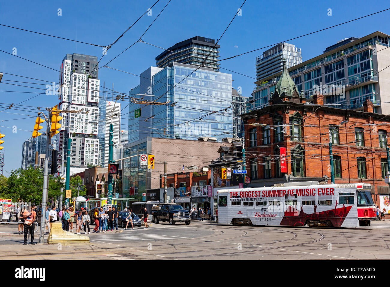 Canada, Provincia di Ontario, città di Toronto, Queen Street West, nuovo quartiere alla moda, incrocio con Spadina Avenue, la linea del tram e il centro della città delle torri Foto Stock