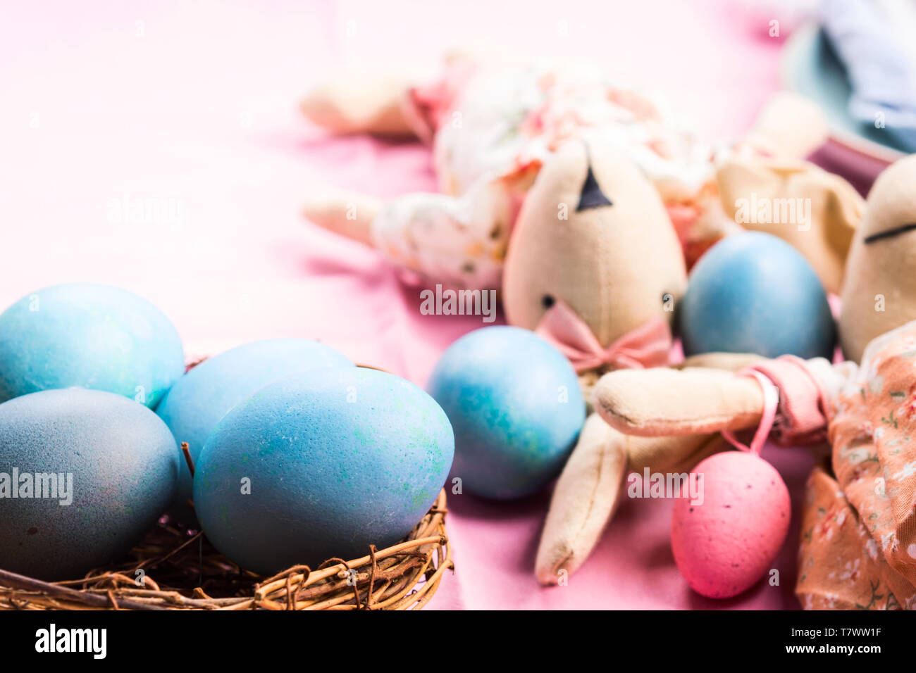Rosa vacanze di pasqua concetto con bunny e colorate in blu le uova sode in un nido di vimini Foto Stock