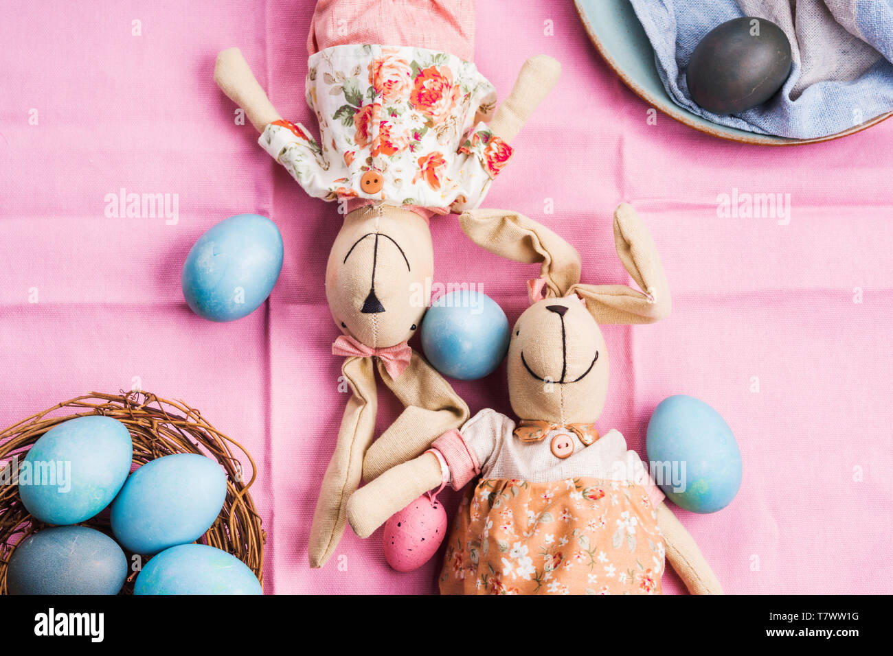 Rosa vacanze di pasqua concetto con coniglietti e colorate in blu le uova sode in un cestello. Decorazioni da tavola laici piatta Foto Stock