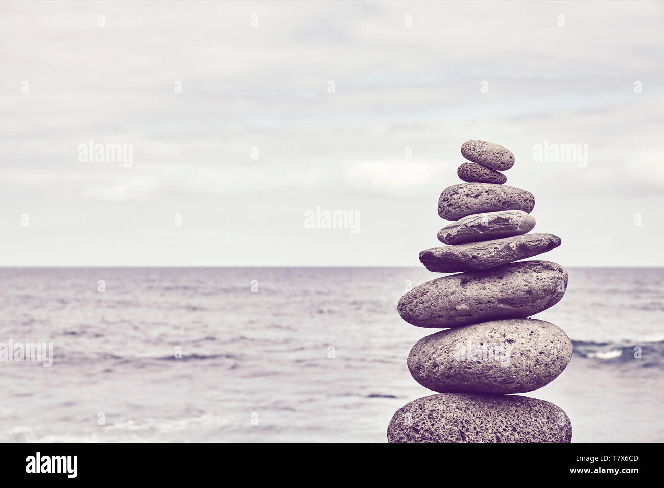 Piramide fatta di pietre su una spiaggia, dai toni di colore dell'immagine. Foto Stock