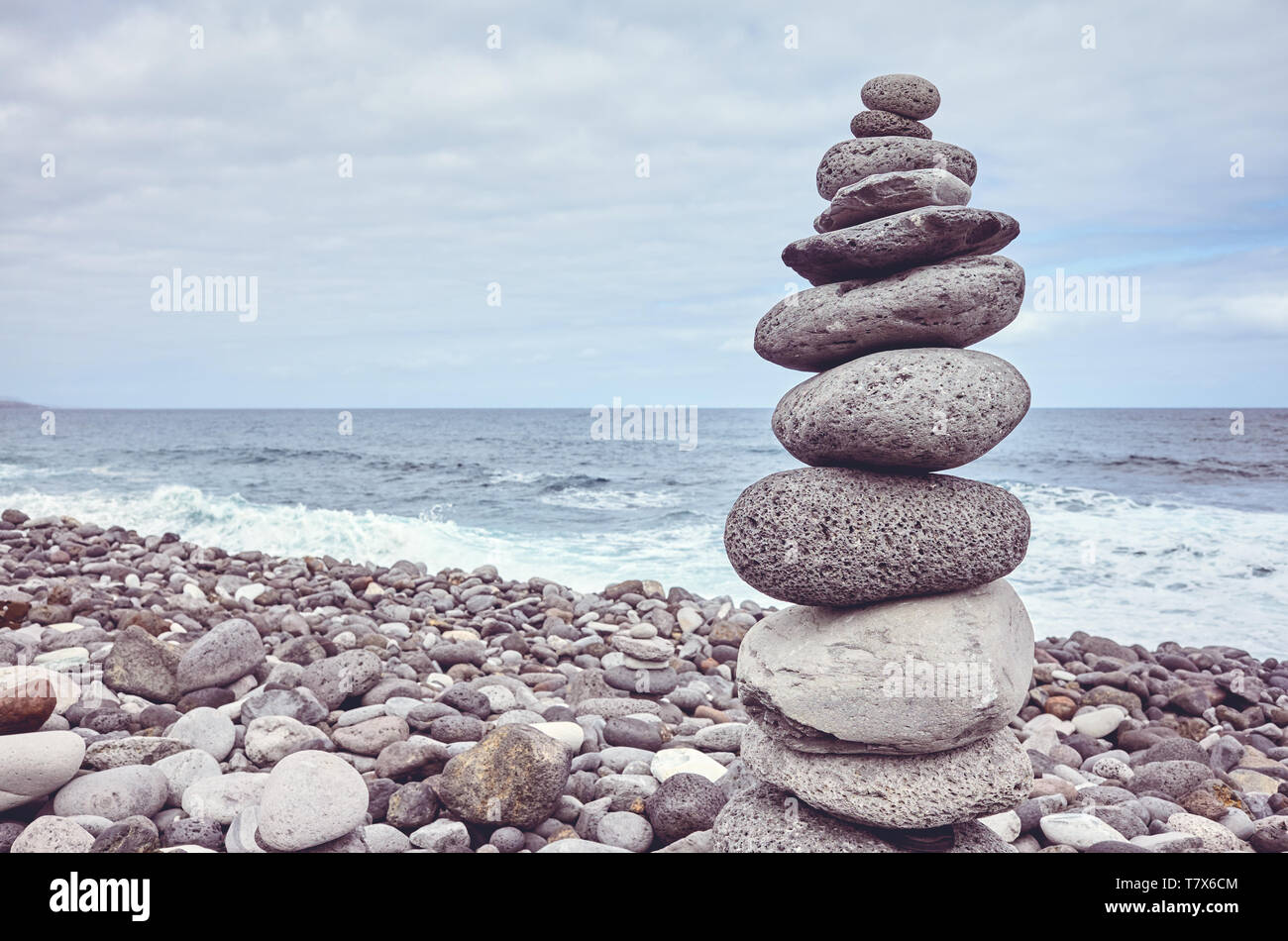 Piramide fatta di pietre su una spiaggia, dai toni di colore dell'immagine. Foto Stock