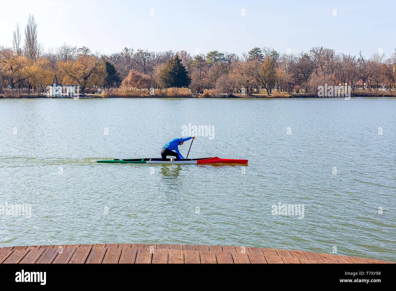 Nyiregyhaza, Ungheria- Febbraio 15, 2019: uomo canottaggio in canoa con pala , in piedi su un ginocchio. Treni atleta sul lago Foto Stock