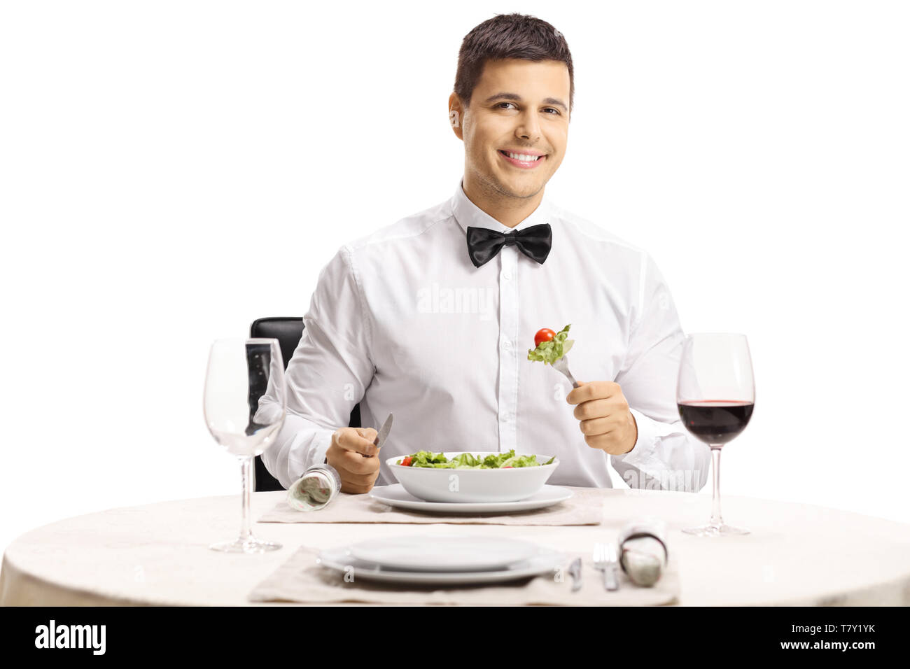 Uomo elegante con un filtro bow tie mangiare insalata presso un ristorante tabella isolati su sfondo bianco Foto Stock
