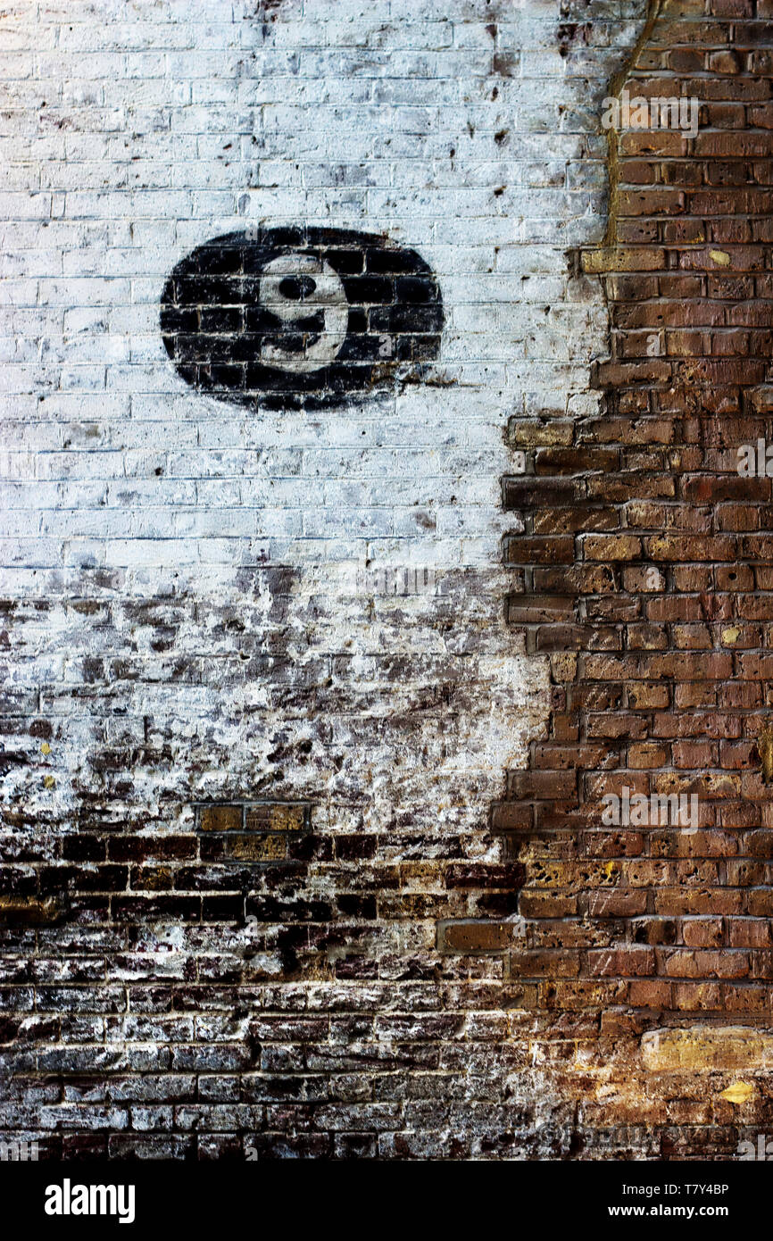 Dettaglio di un vecchio edificio adibito a magazzino interno mostra mattoni dipinto di numeri e altre funzioni Foto Stock
