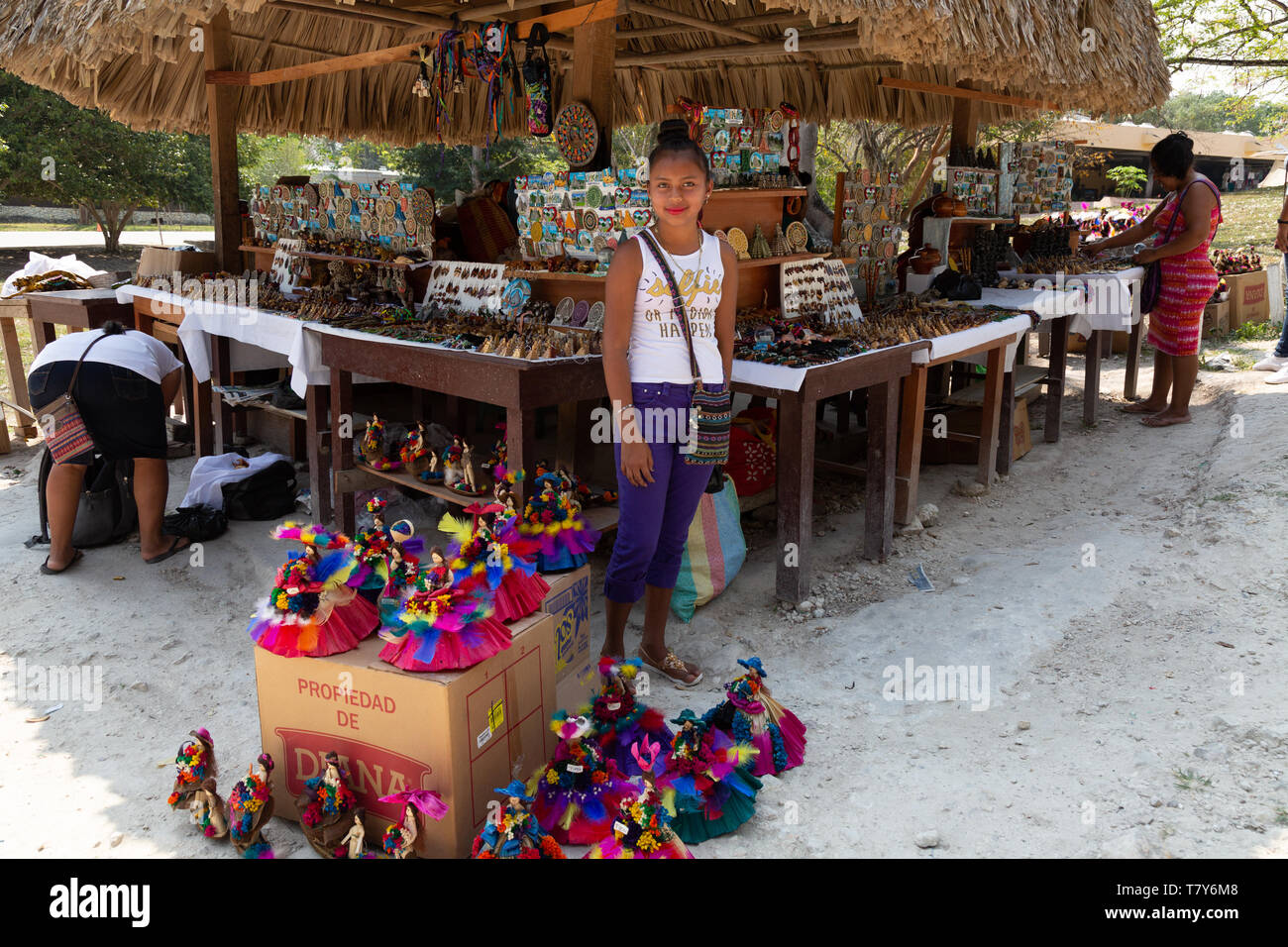 America centrale del mercato e di stallo donna adolescente commerciante vendita di bambole e di altri oggetti di artigianato; Tikal, Guatemala America Latina Foto Stock