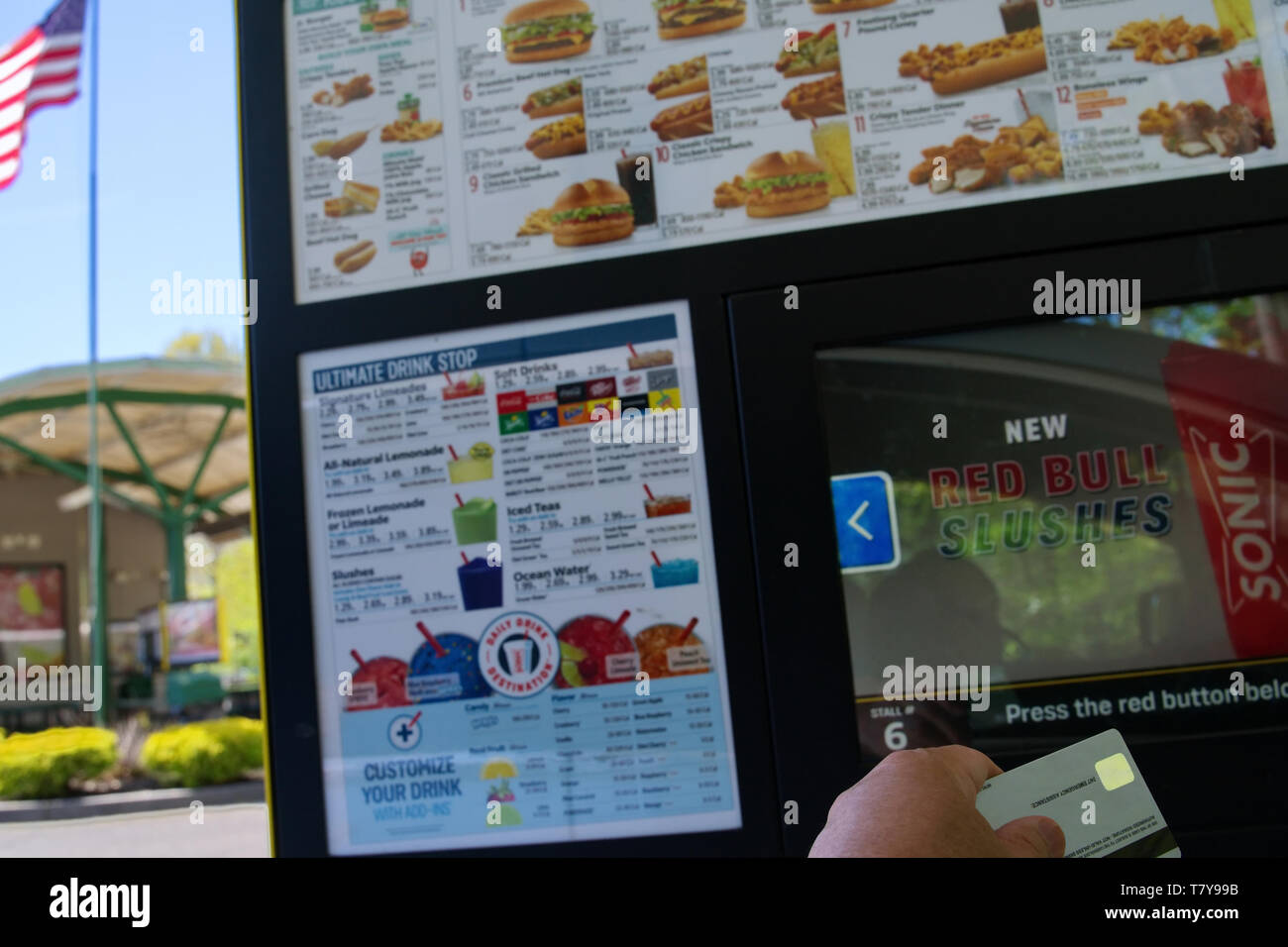 Wallingford, CT, Stati Uniti d'America. Maggio 2019. Mano che tiene una mirata carta di credito pronta per essere caricata in un fast food menu automatizzati kiosk. Foto Stock