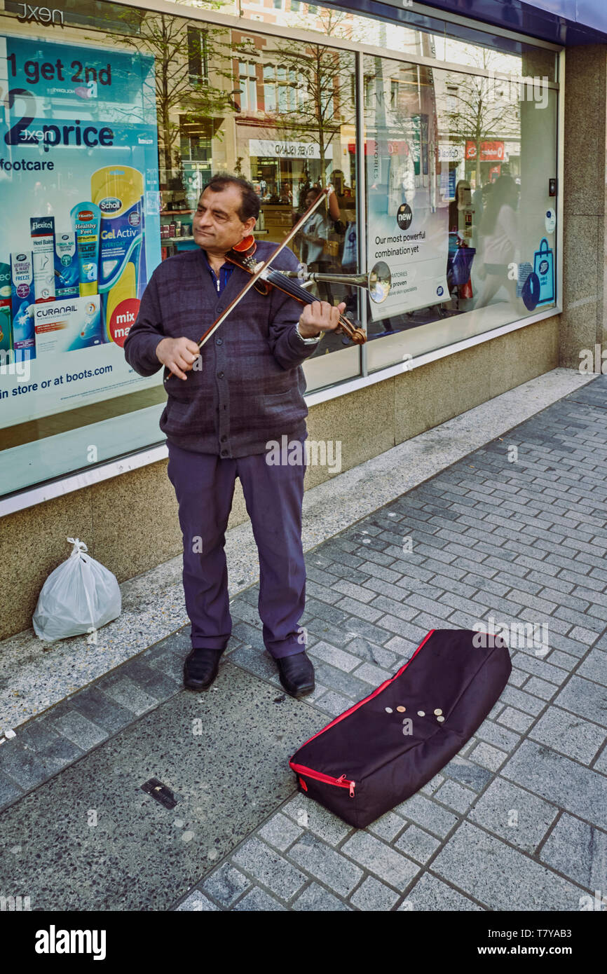 Suonatore ambulante di una riproduzione di un violino Stoviol nel centro di Belfast, Irlanda del Nord Foto Stock