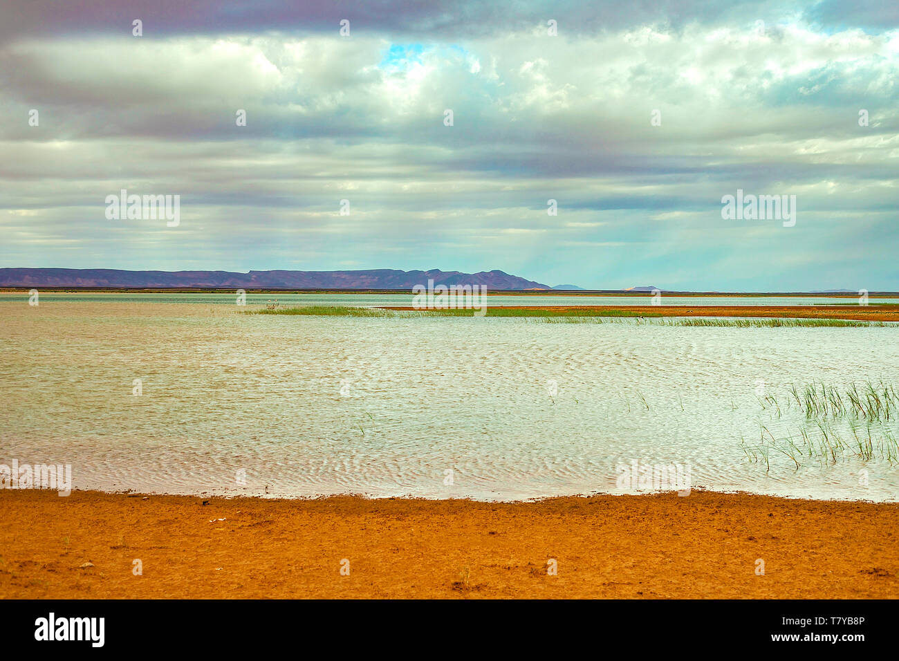 Il lago in Marocco all'alba ai piedi del deserto del Sahara. Il sole splende attraverso le nuvole. Foto Stock