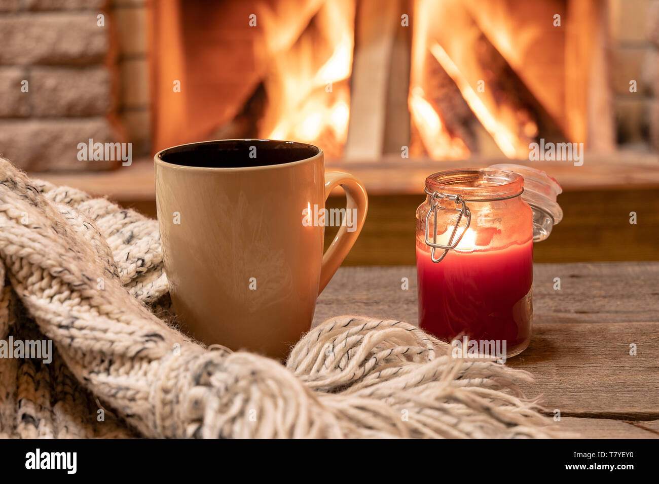 Grande tazza di tè caldo e una candela , Lana sciarpa, vicino al caminetto, in country house, hygge, casa dolce casa. Foto Stock