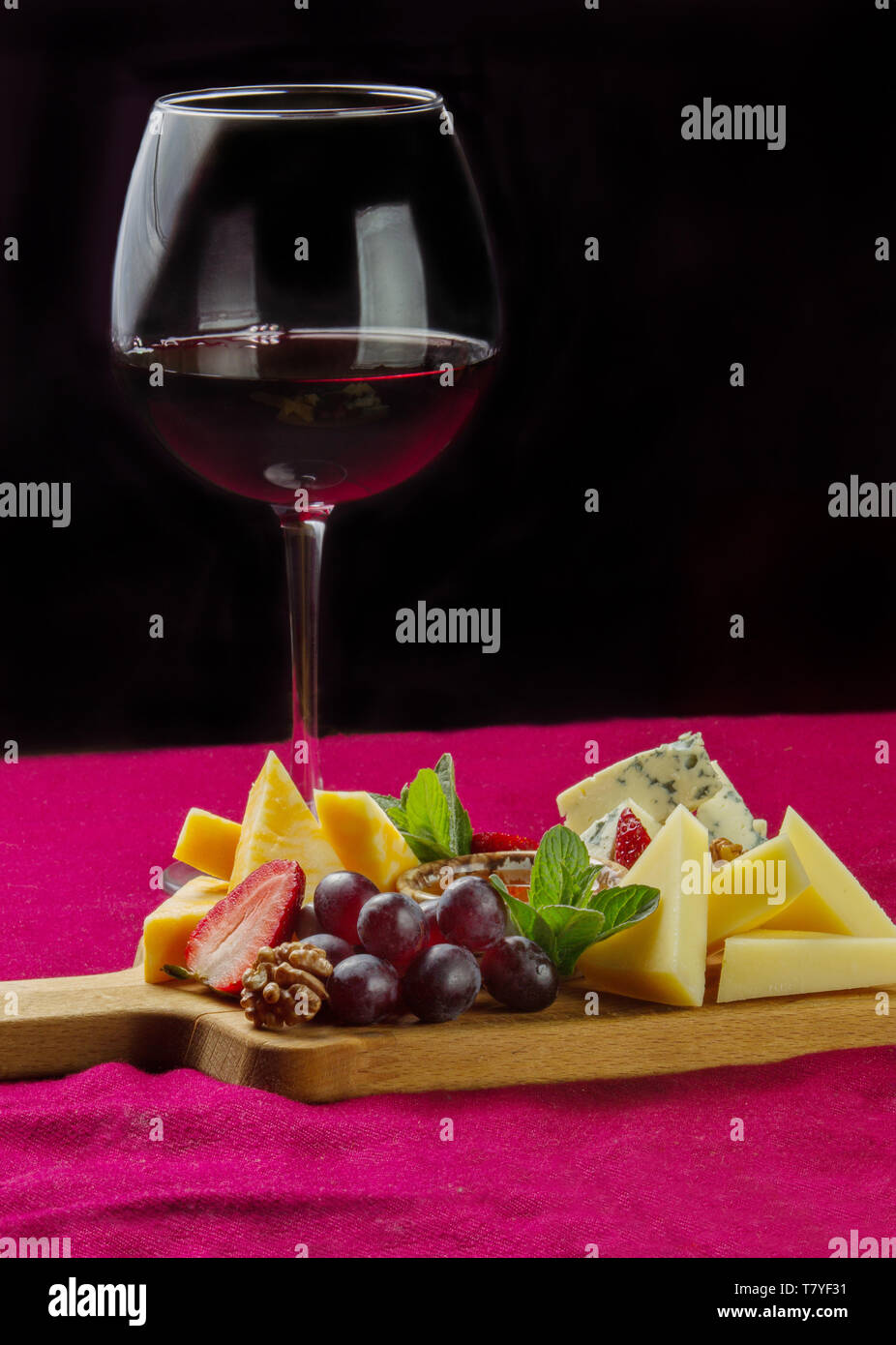 Diversi tipi di formaggio Parmigiano-,dor blu, formaggio di marmo, menta, uva e un bicchiere di vino rosso Foto Stock