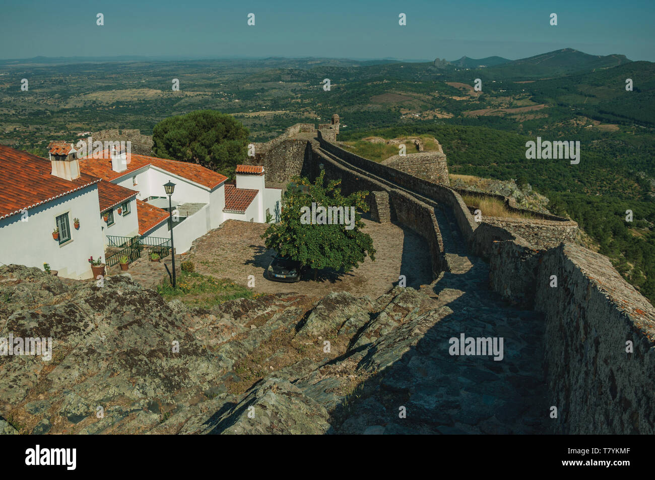 Le vecchie case e muro di pietra sulla cresta e paesaggio coperto da alberi a Marvao. Un borgo medievale arroccato su una rupe in Portogallo. Foto Stock