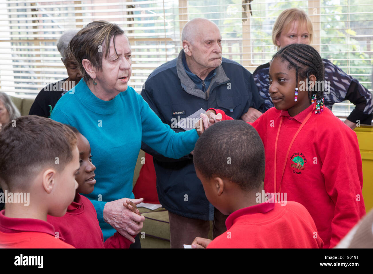 I bambini della scuola di visitare una casa di cura per cantare e ballare con i clienti, alcuni dei quali sono anziani e alcune dispongono di demenza. Foto Stock