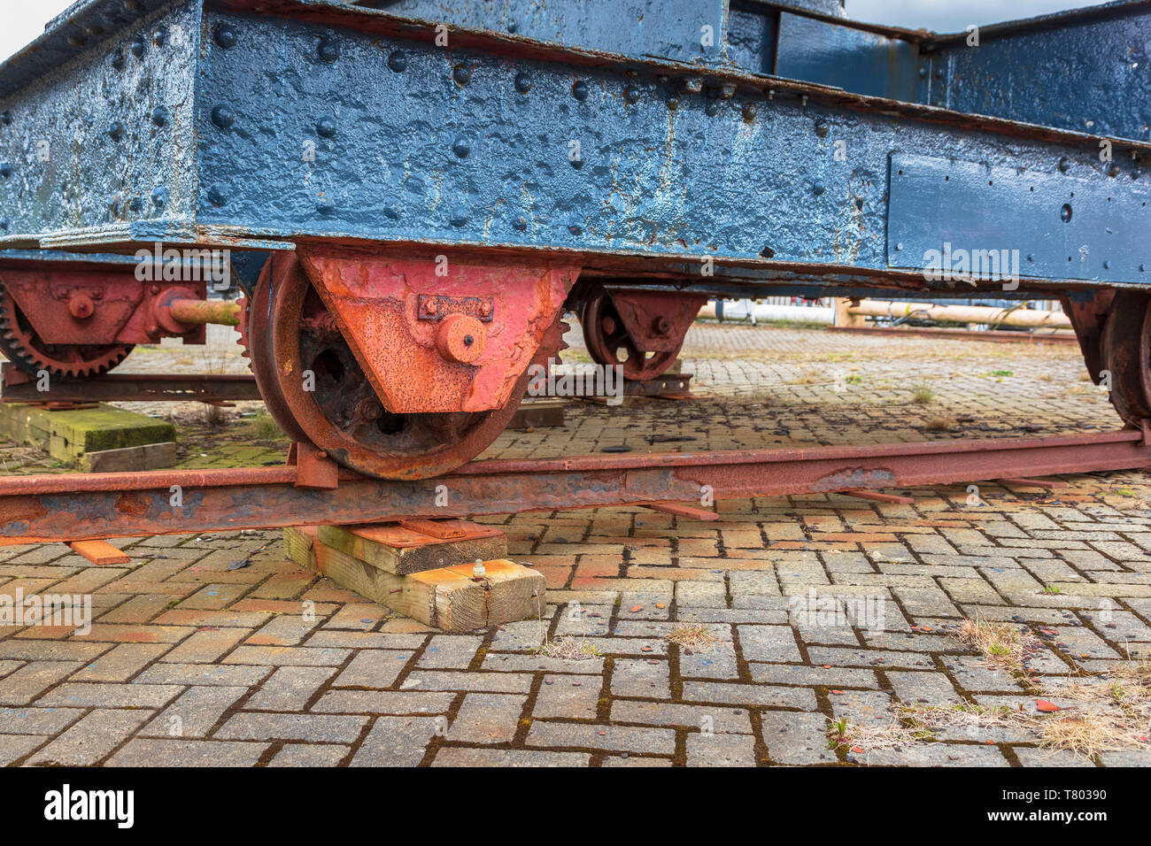 Vecchio e ruggine carro ferroviario con blu scuro iron body shell e ruggine ruote dentate utilizzato come una piattaforma mobile per una piccola gru, Ayrshire, in Scozia Foto Stock