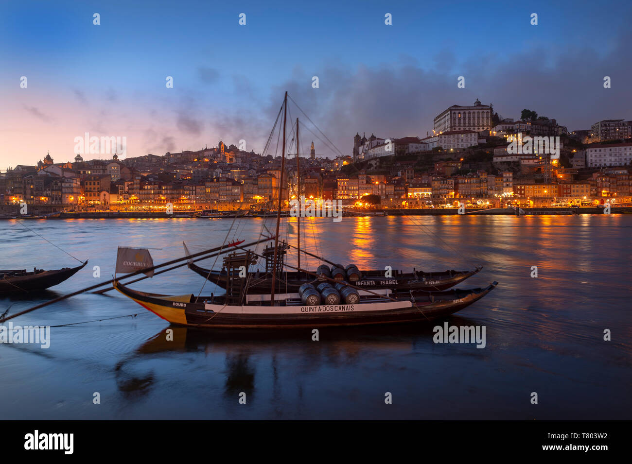 Porto barche ormeggiate sul Rio Douro con Porto cityscape in background di notte Foto Stock